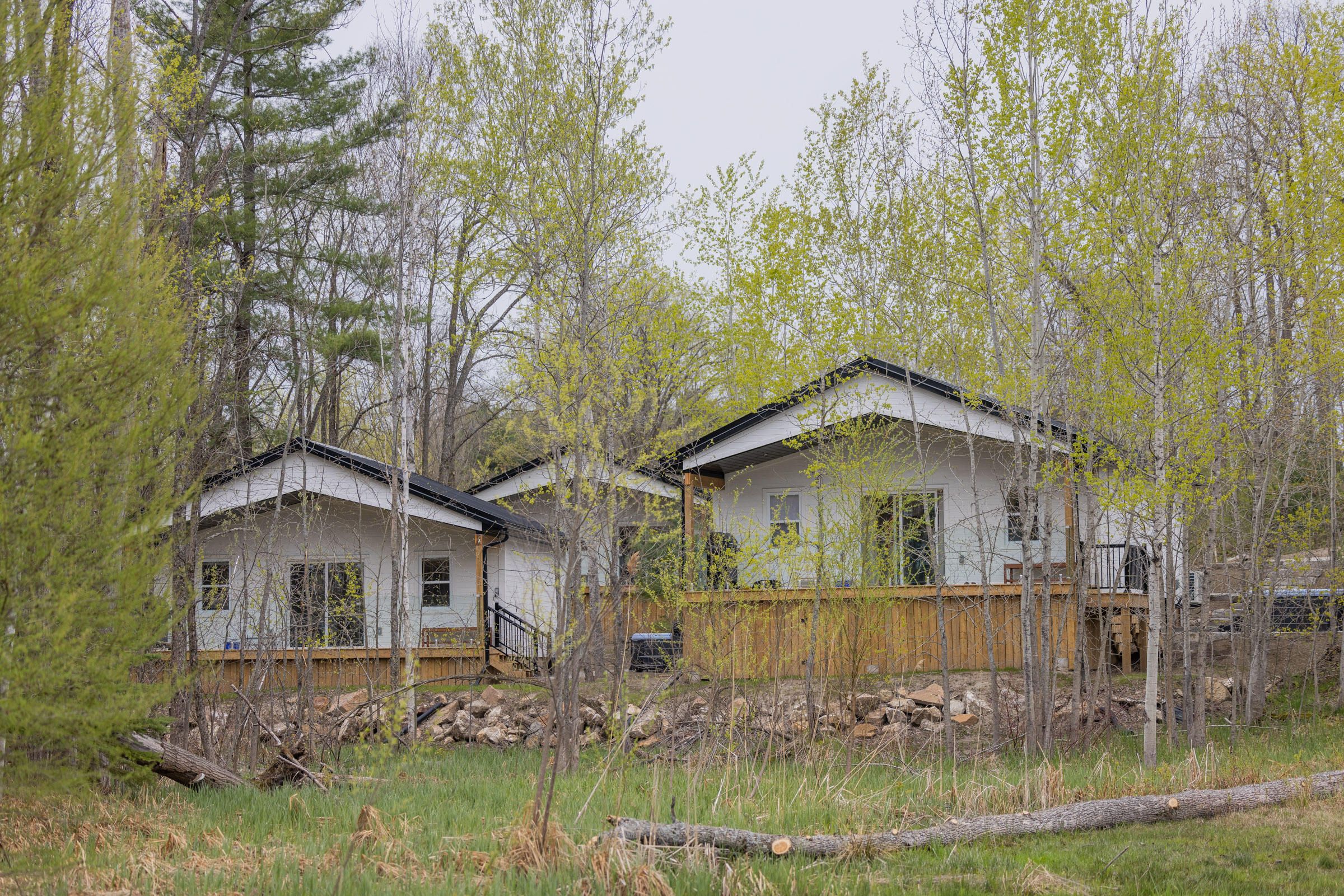 Two newly built cabins with wooden decks among spring trees.