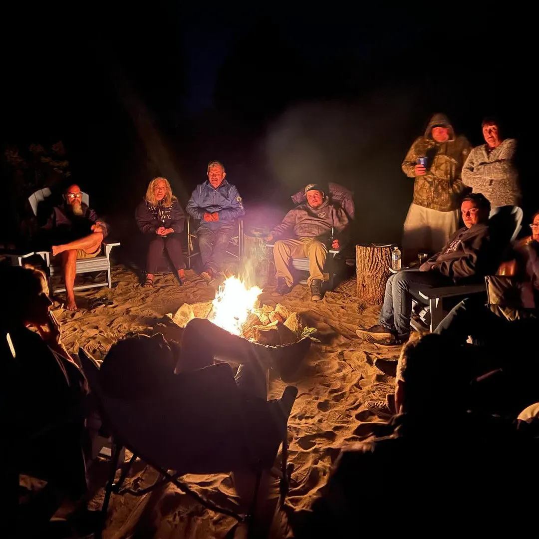 A group sitting around an outdoor fire in the evening.
